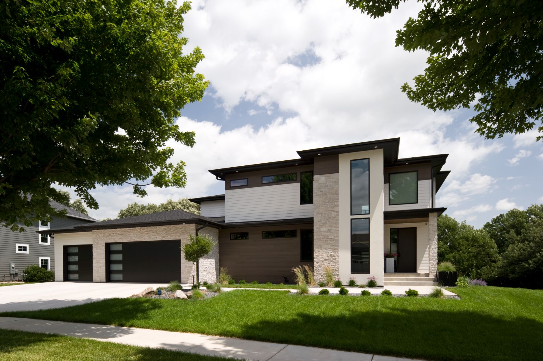Modern white and stone exterior with a black garage door
