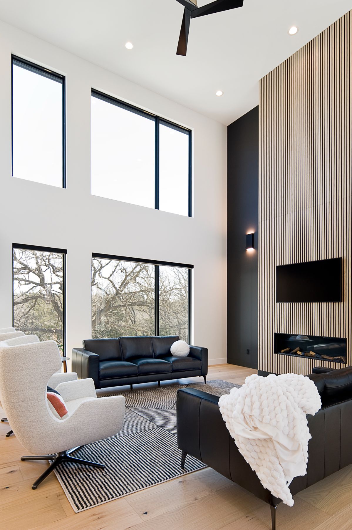 Two-story black slat feature wall with leather seating and a zebra rug