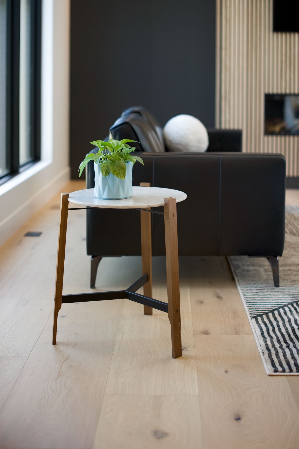 Black leather sofa and a walnut side table by the slat wall