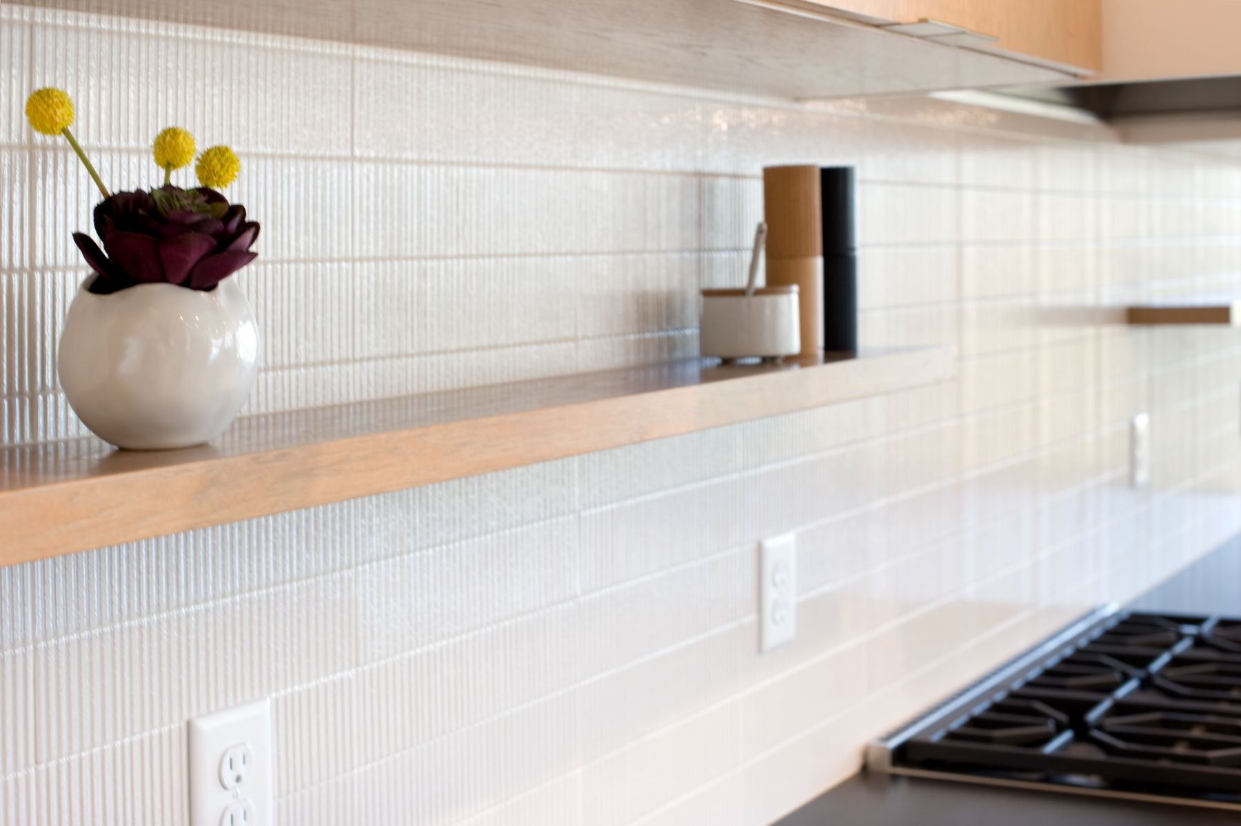 Fluted white tile backsplash, oak shelf and yellow billy buttons