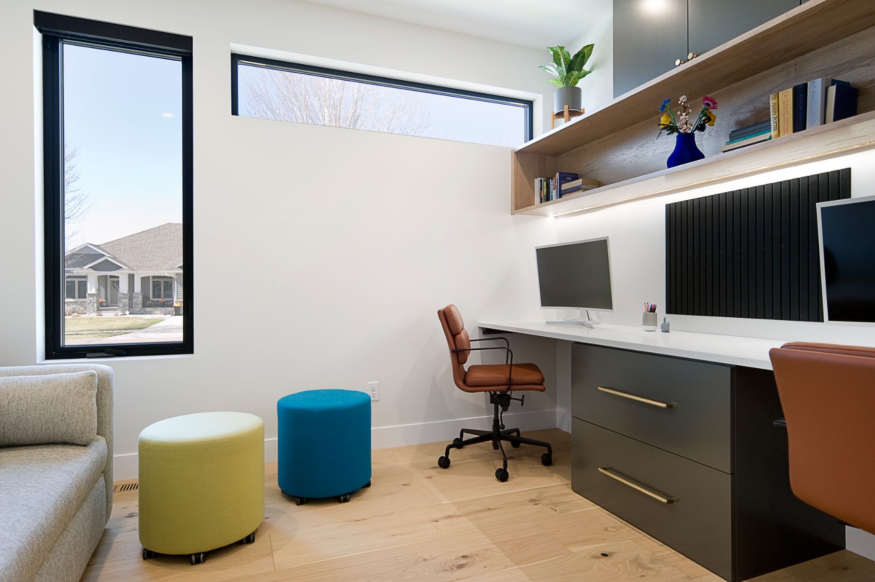 Home office with a long white desk, teal and citron poufs and a bouclé chair