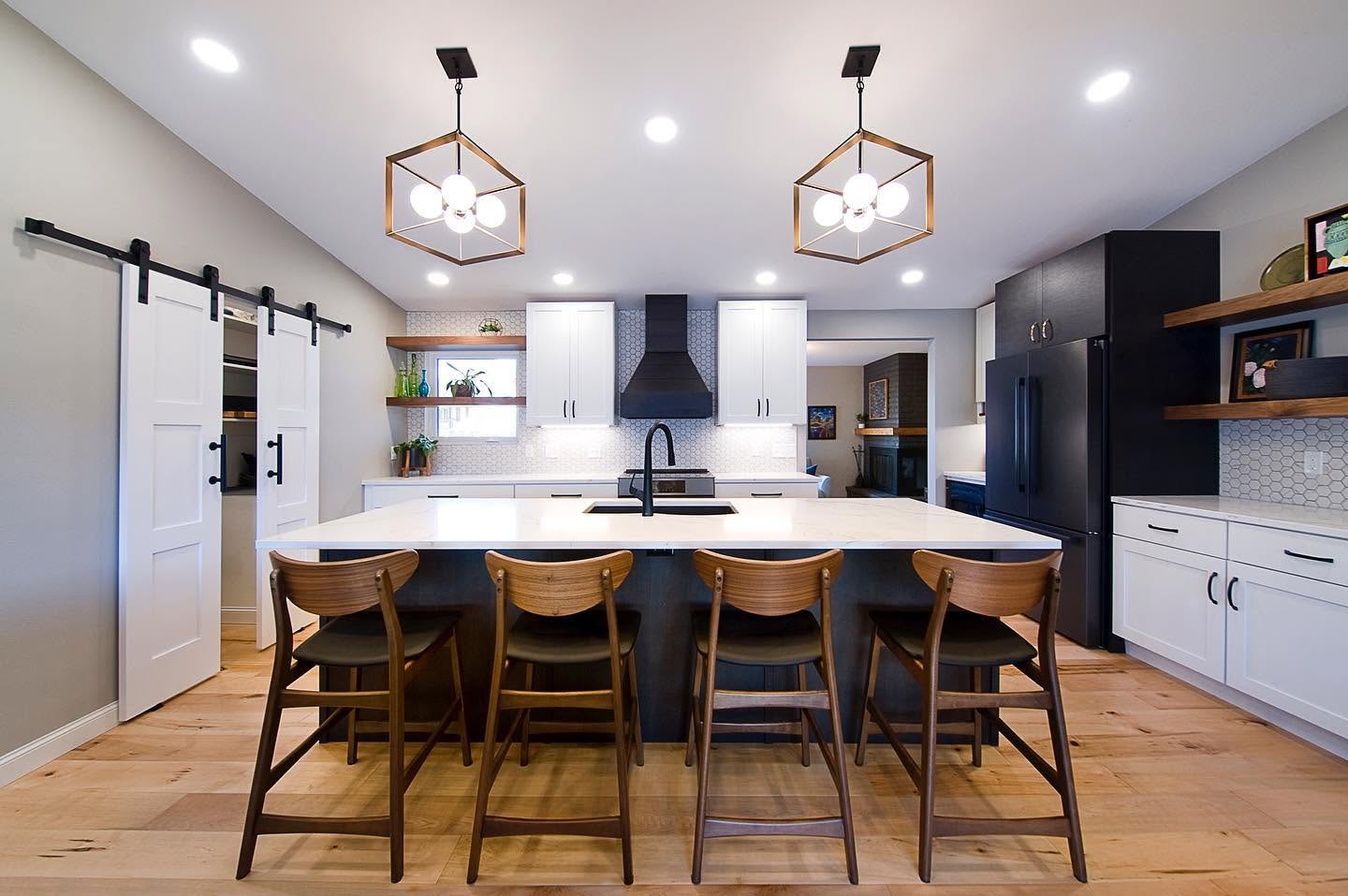 A calm white-oak kitchen with matte-black accents and a barn door